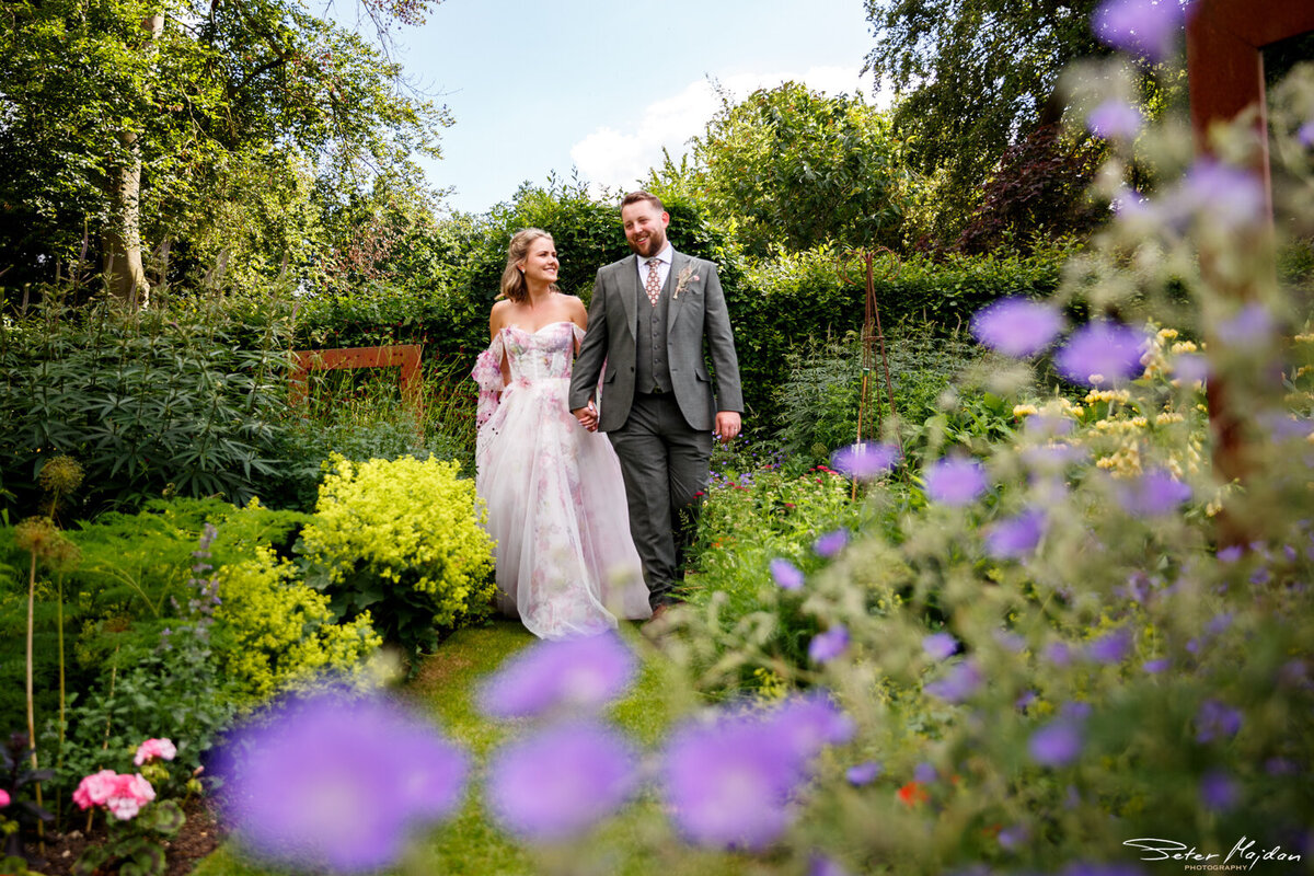 bride and groom walking through garden