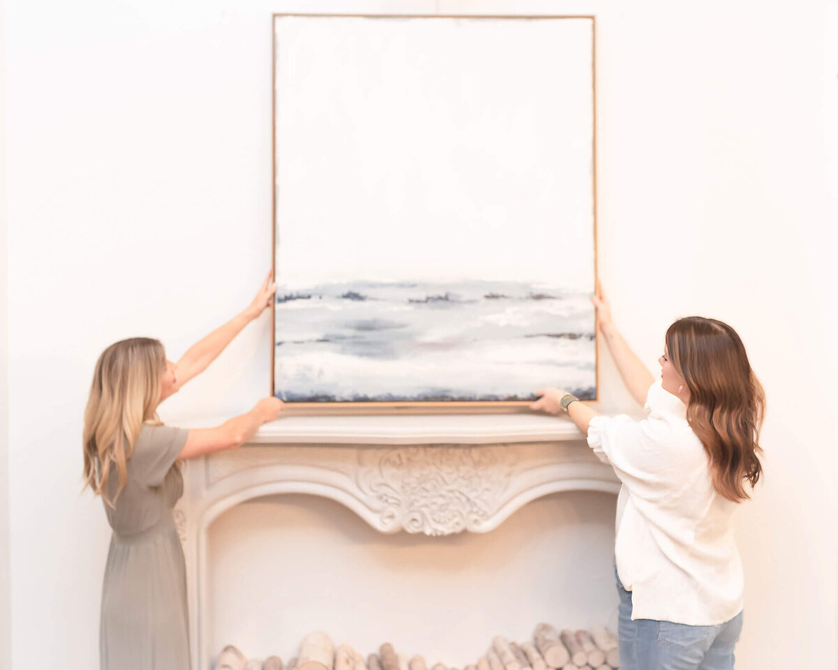two women interior designers hanging wall art together