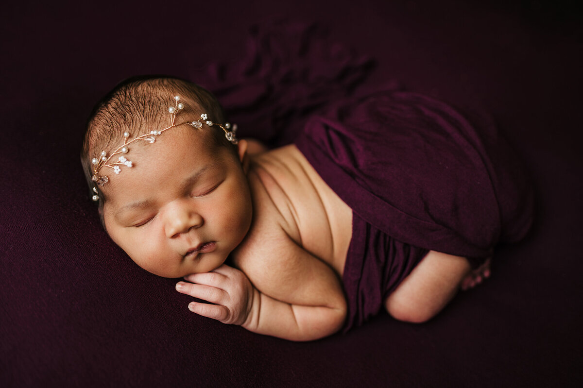 Sleeping baby laying on a purple background wrapped in purple