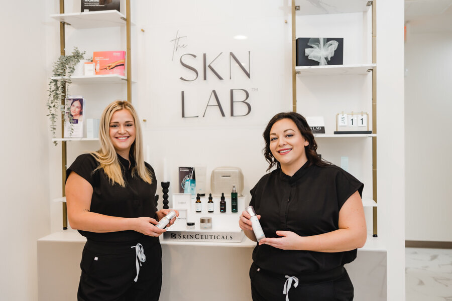 women standing in front of skinlab products and sign