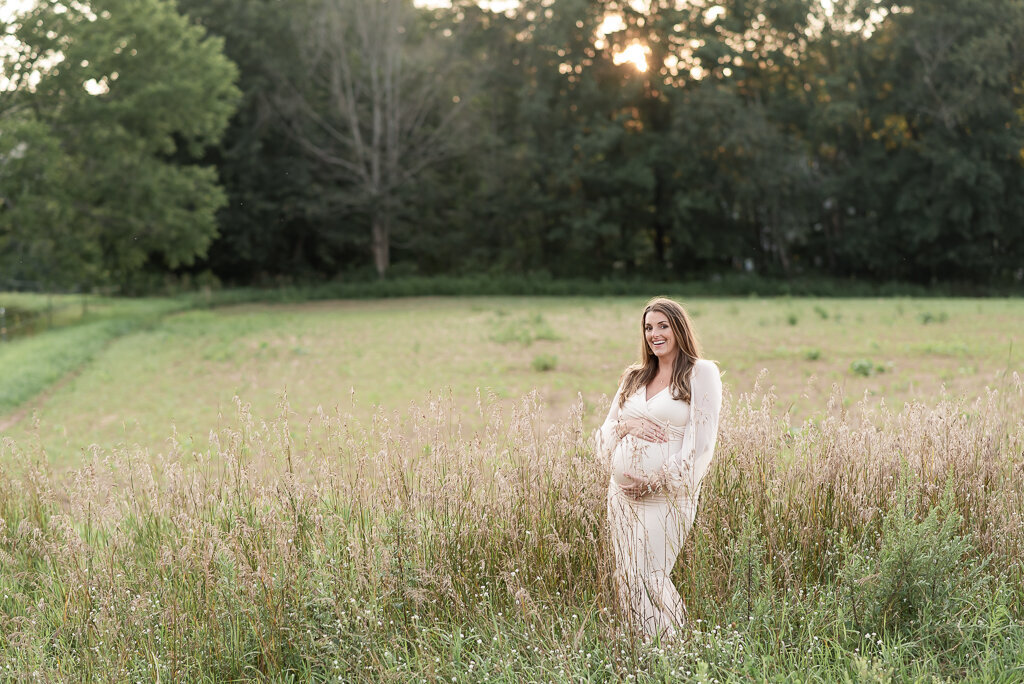 Pregnant mom standing in field in white dress at summer maternity session | Sharon Leger Photography | CT Newborn & Family Photographer | Canton, Connecticut