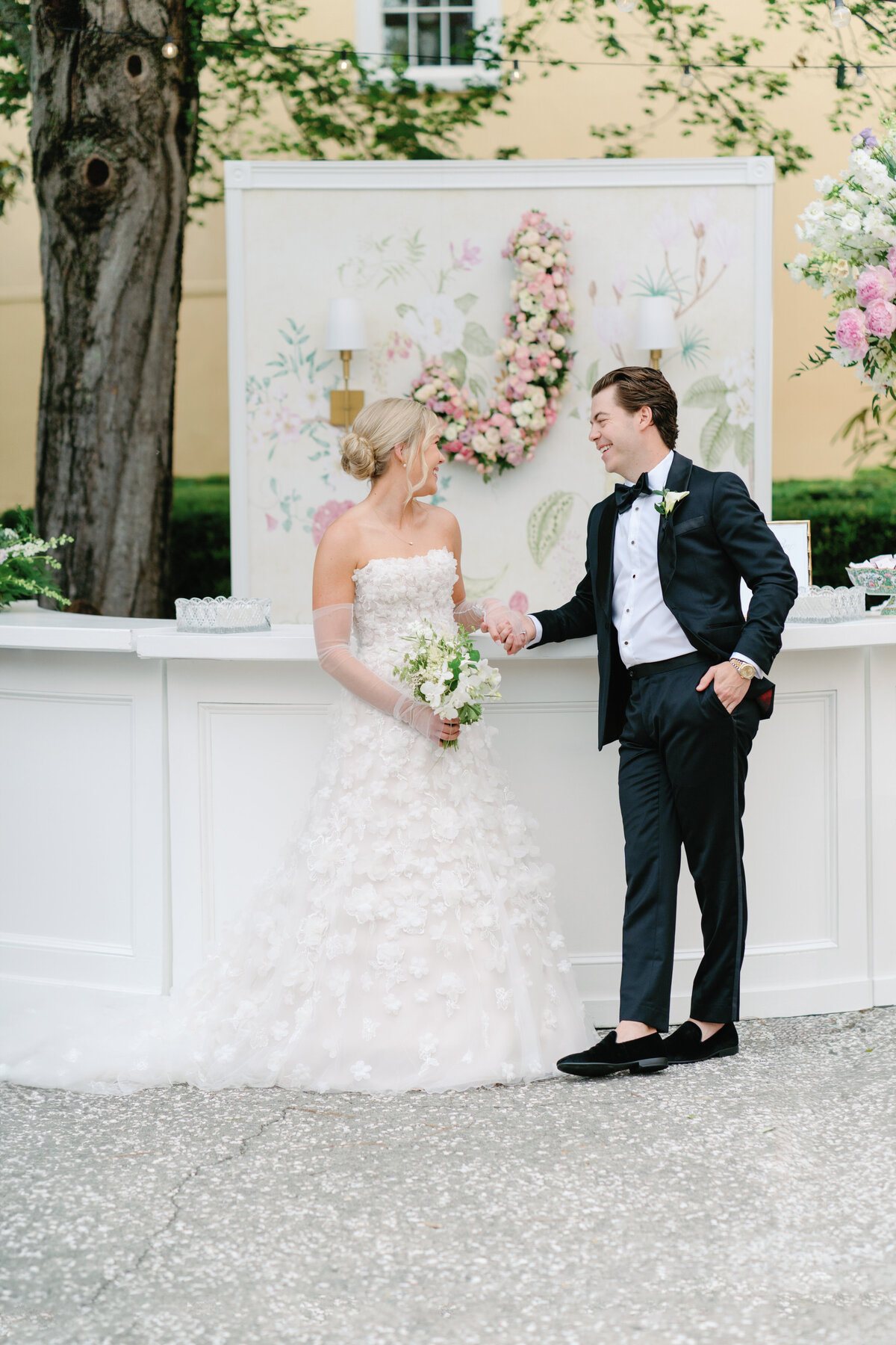 Bride and groom in front of custom bar with floral installation. Historic Charleston wedding venue with yellow walls.