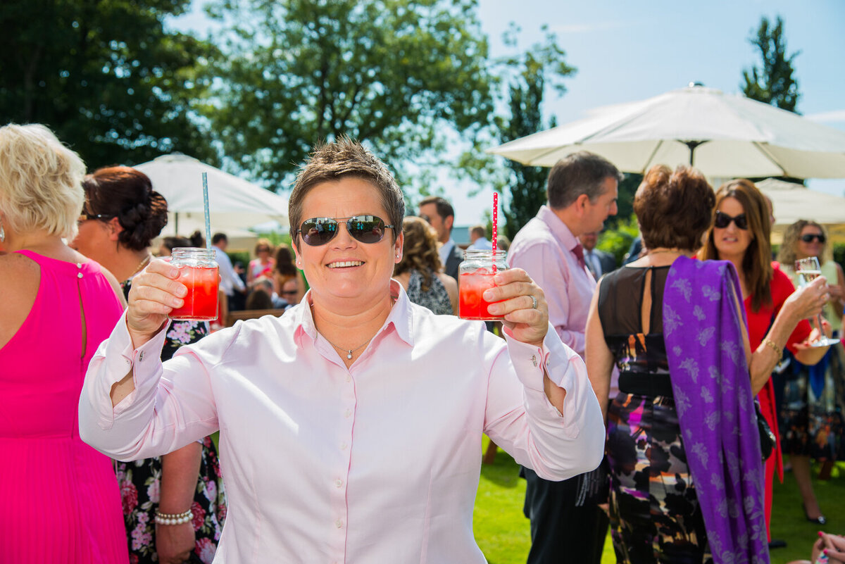 wedding guest holding colourful cocktails in garden