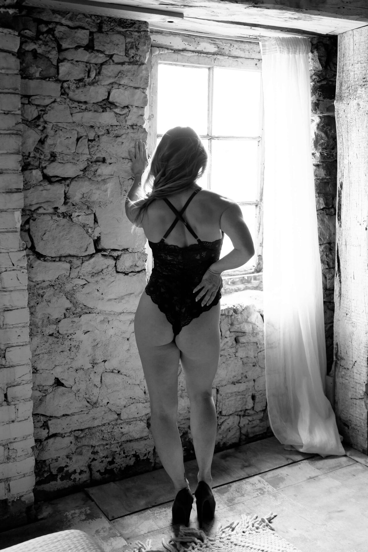 Woman in lingerie and high heels facing a brick wall for her Mississauga boudoir photography session