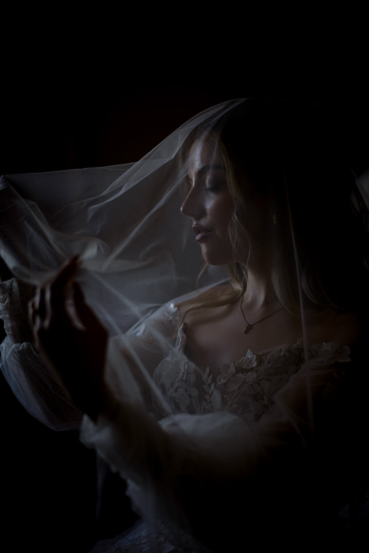 Braut hält  mit geschlossenen Augen ihren Schleier vor ihrem Gesicht