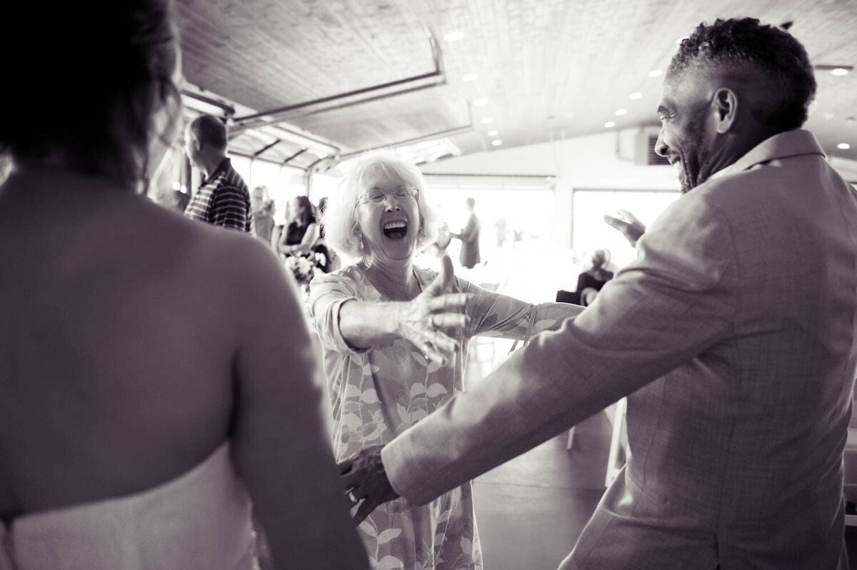 an overly excited woman screams and runs with arms outstretched to hug a groom at his wedding
