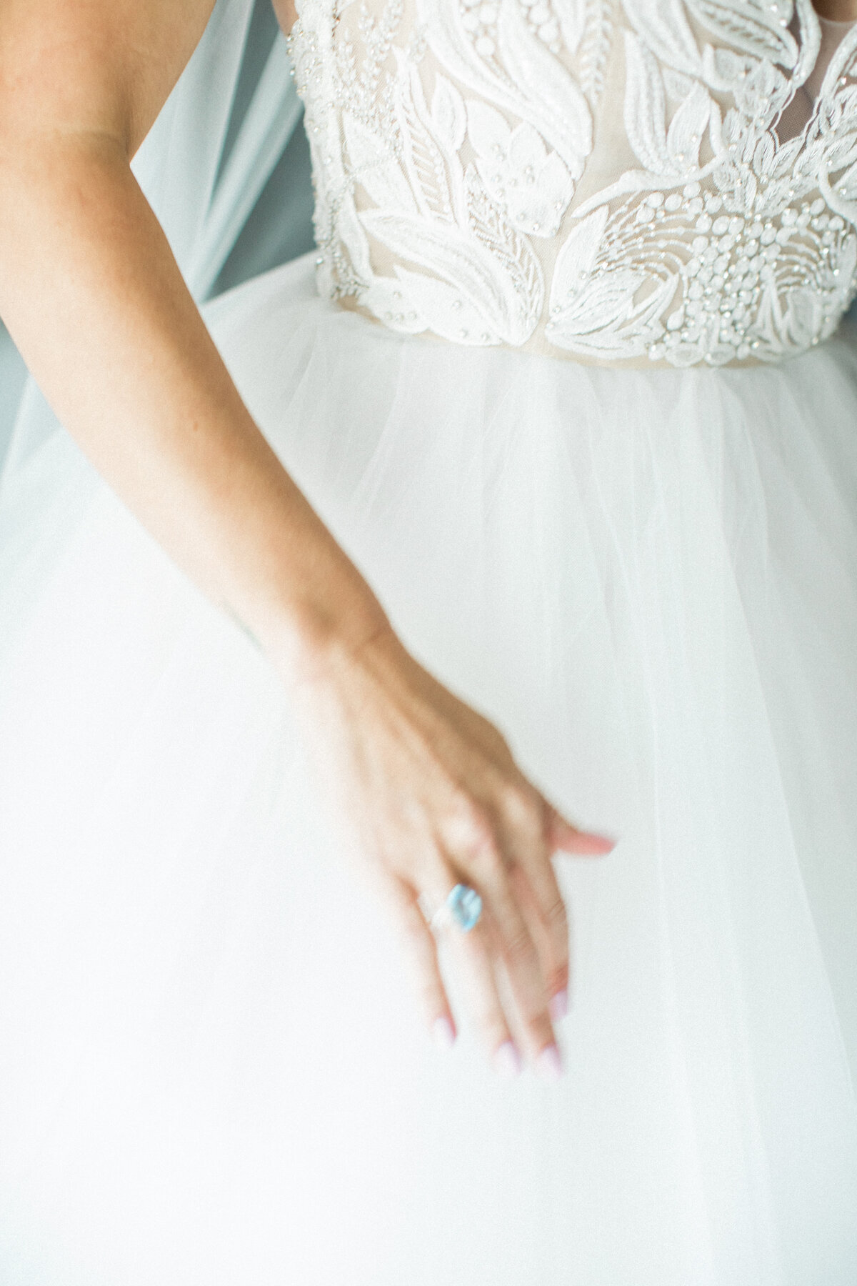 Detail shot of a bride's wedding dress and engagement ring