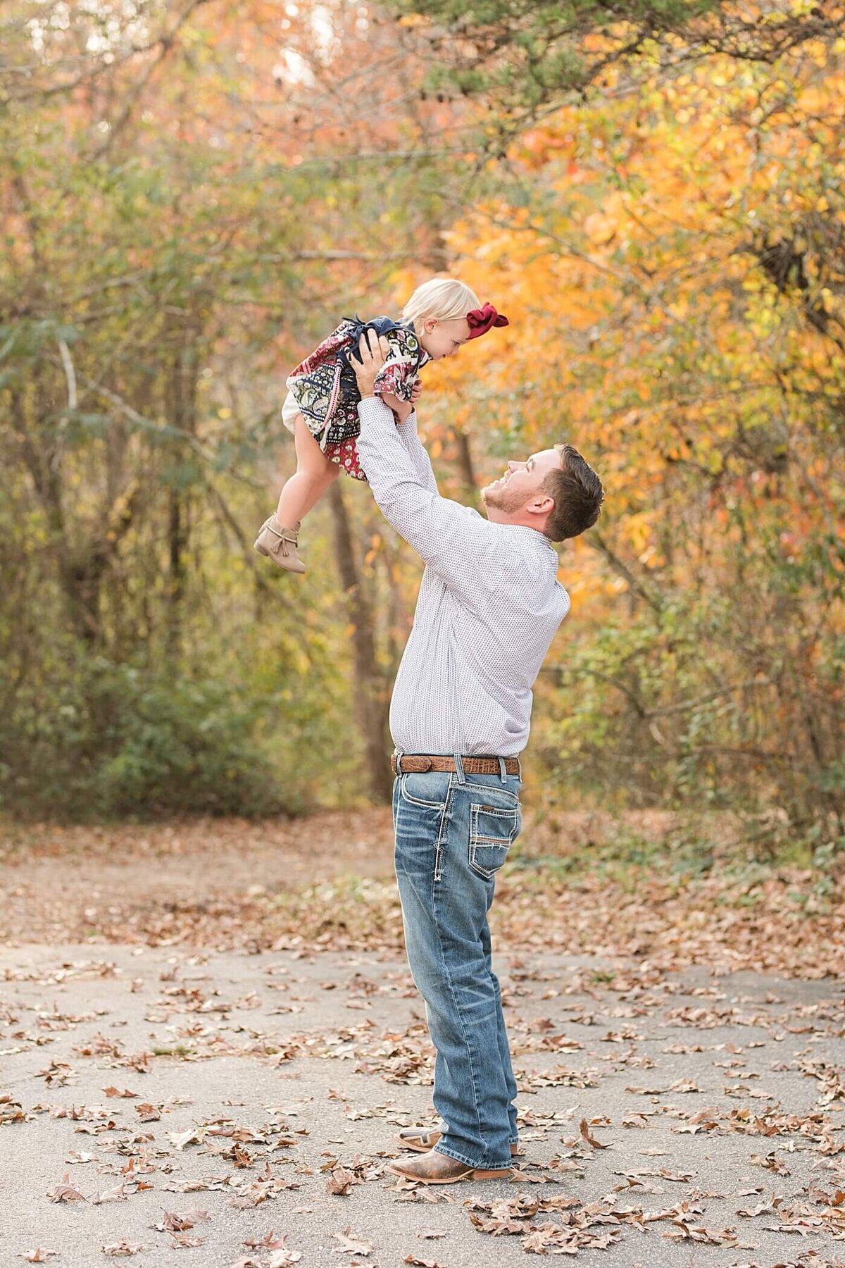 dad lifting daughter into the air furing their family photoshoot in hickory nc at glenn hilton park