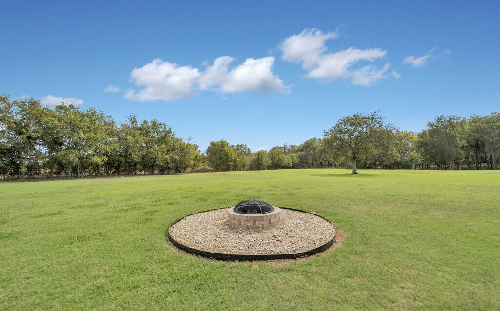 Outdoor firepit in spacious yard in this four-bedroom, four-bathroom vacation rental home and guest house with free WiFi, fully equipped kitchen, firepit and room for 10 in Waco, TX.