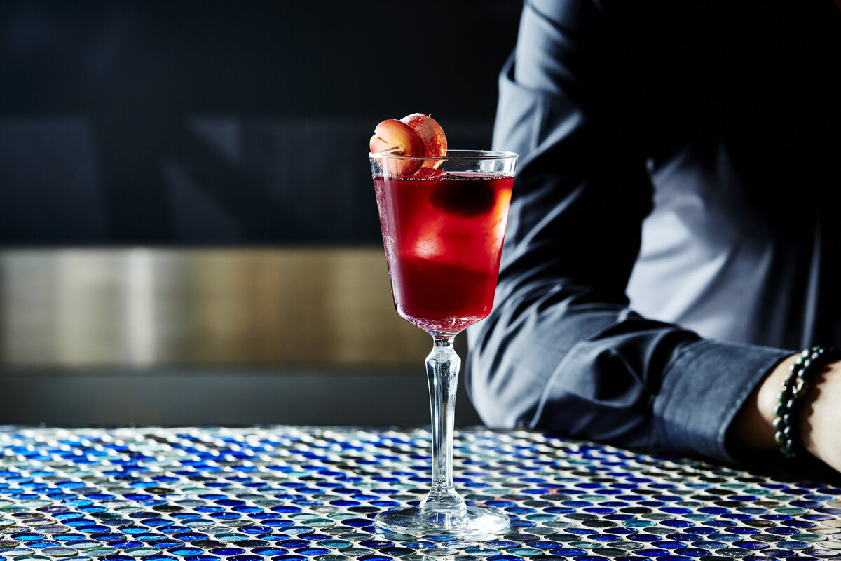 A stemmed glass with a cocktail topped with fruit.