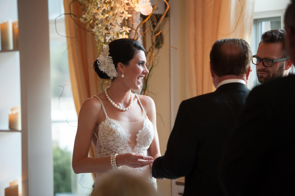 Bride laughing during the ceremony while placing the ring on groom's finger