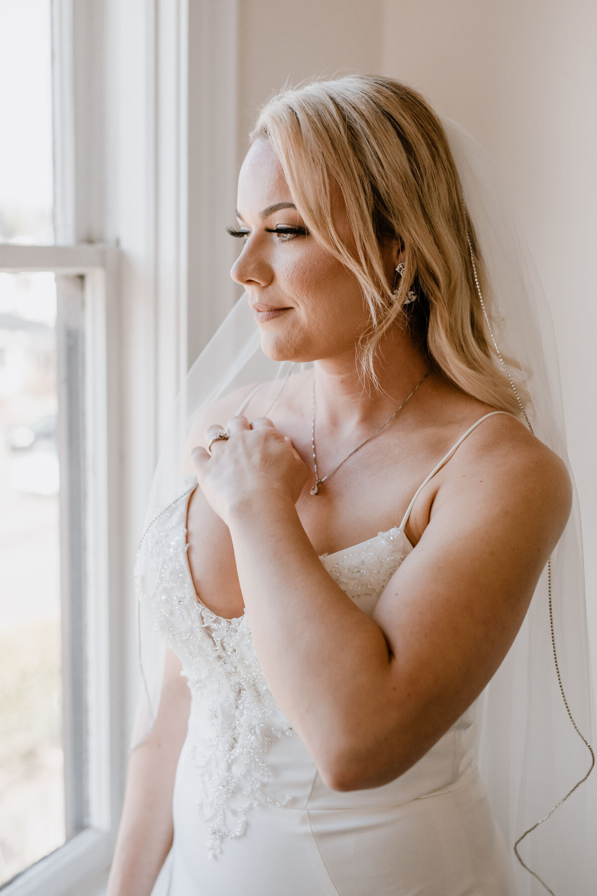 bride with white veil looks out the window