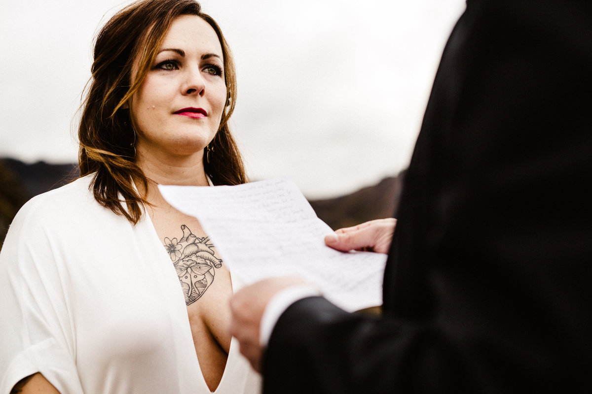 bride with chest tattoo holds back tears during elopement at hatcher pass