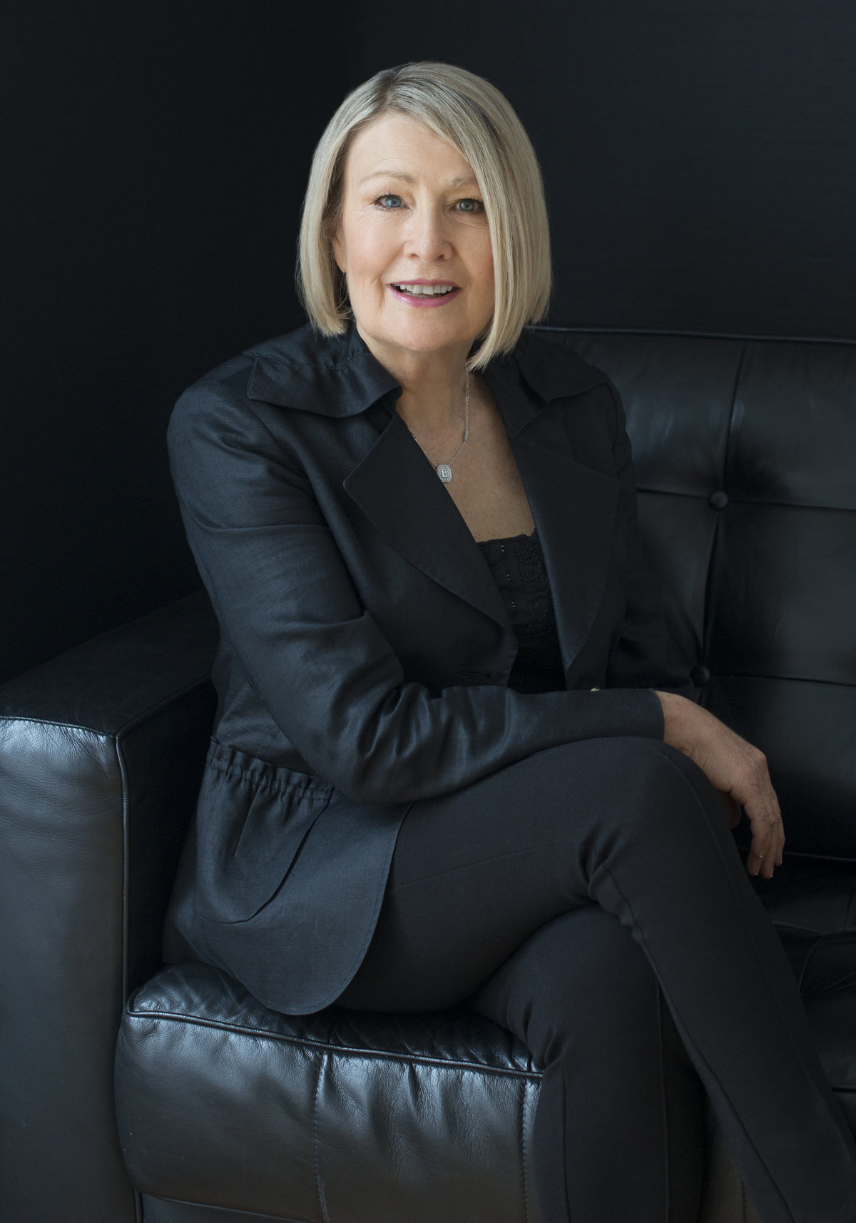 woman Ceo  headshot  photography by puja misra  specialist in womens  photography sitting on black couch wearing black formal  jacket