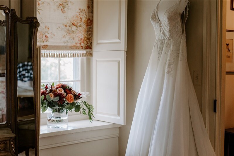 Brides dress and bridal bouquet in front of a window