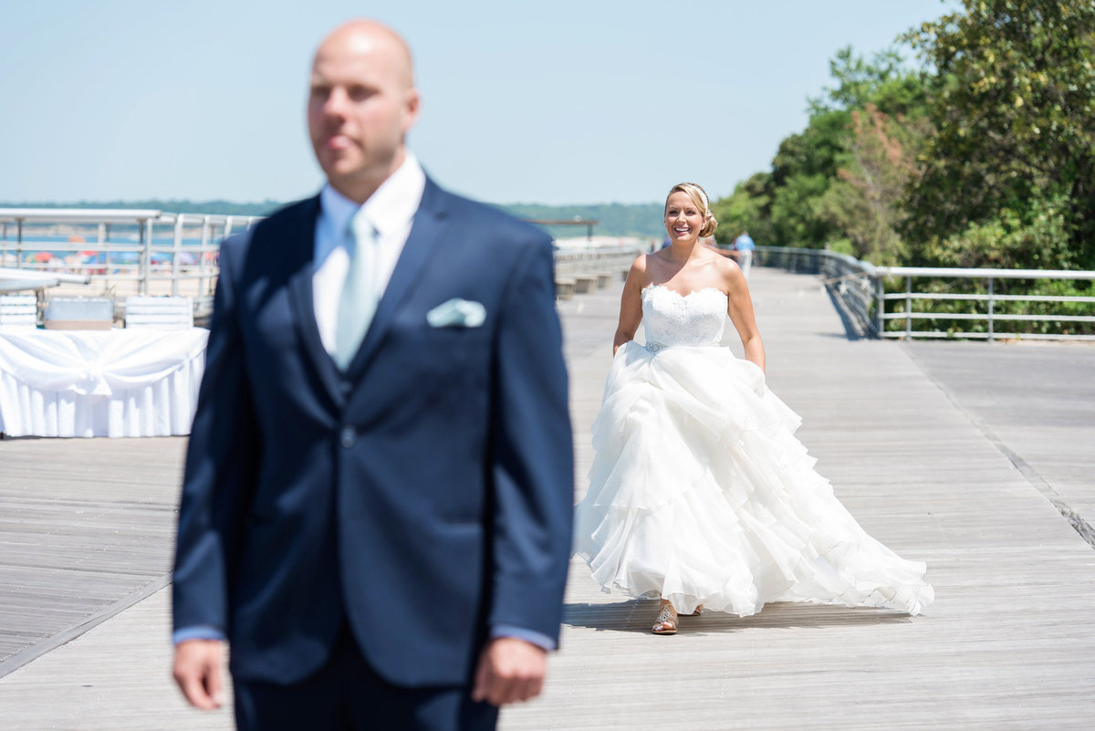 photo of bride and groom before the first look on the boardwalk for wedding reception at Pavilion at Sunken Meadow