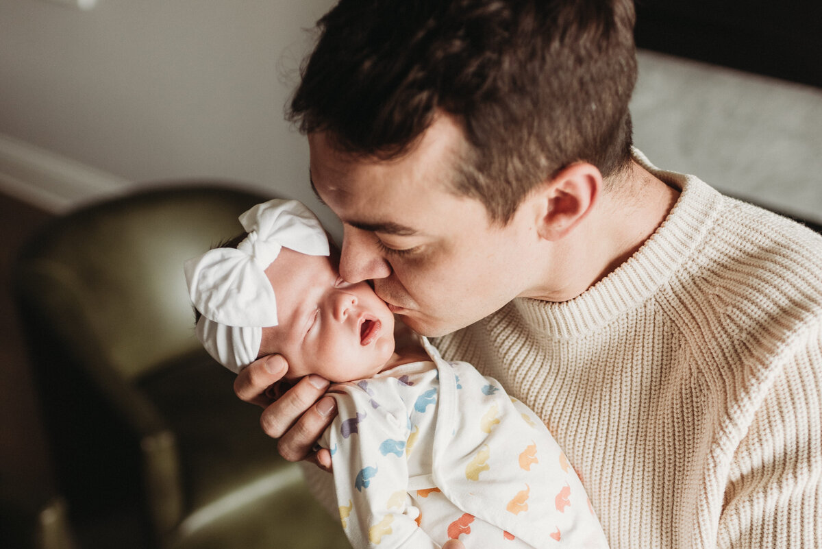 Dad holding and kissing newborn baby