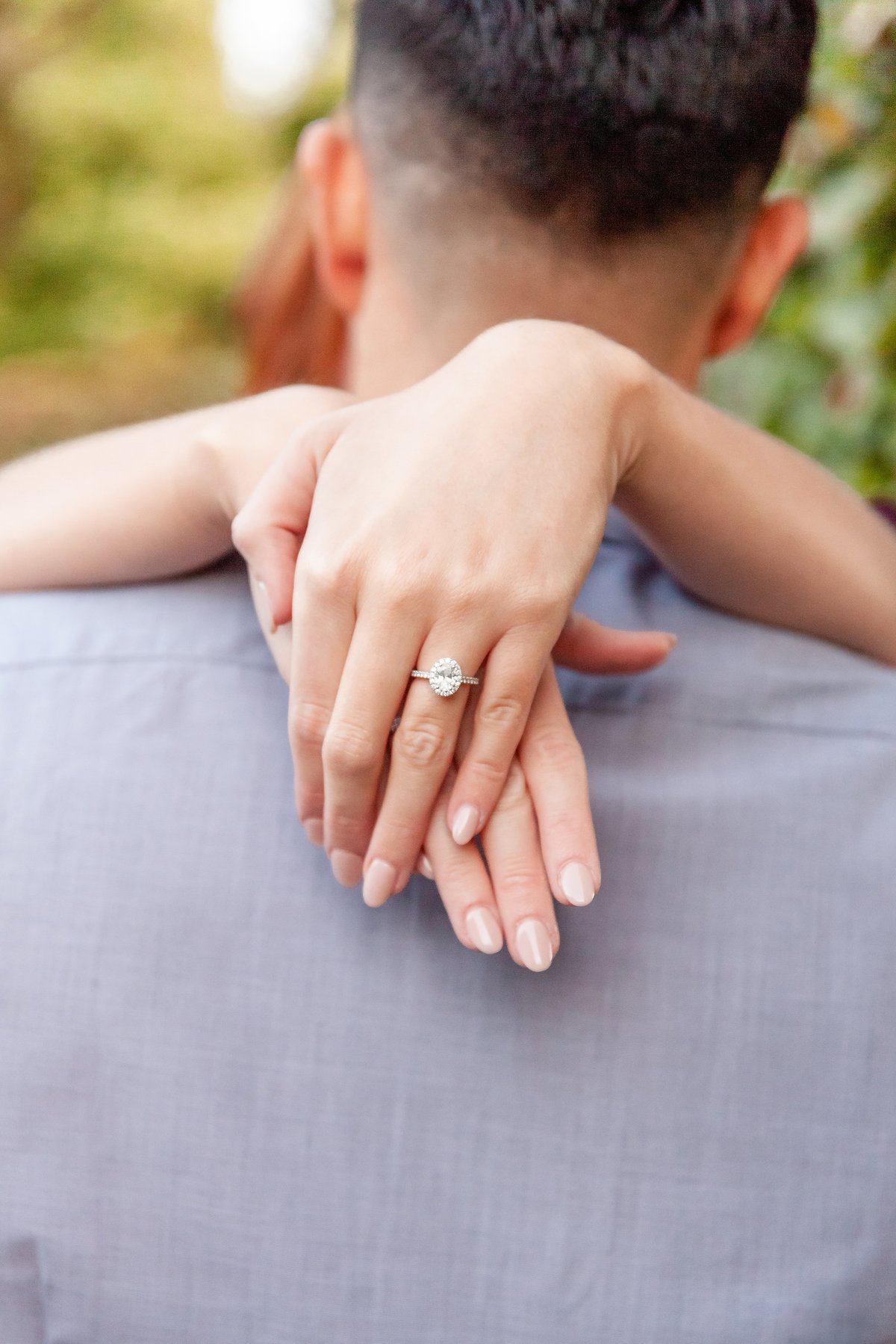 Girl-rests-arms-on-his-shoulders-and-shows-her-Engagement-ring-at-Niagara-Boutanical-Gardens