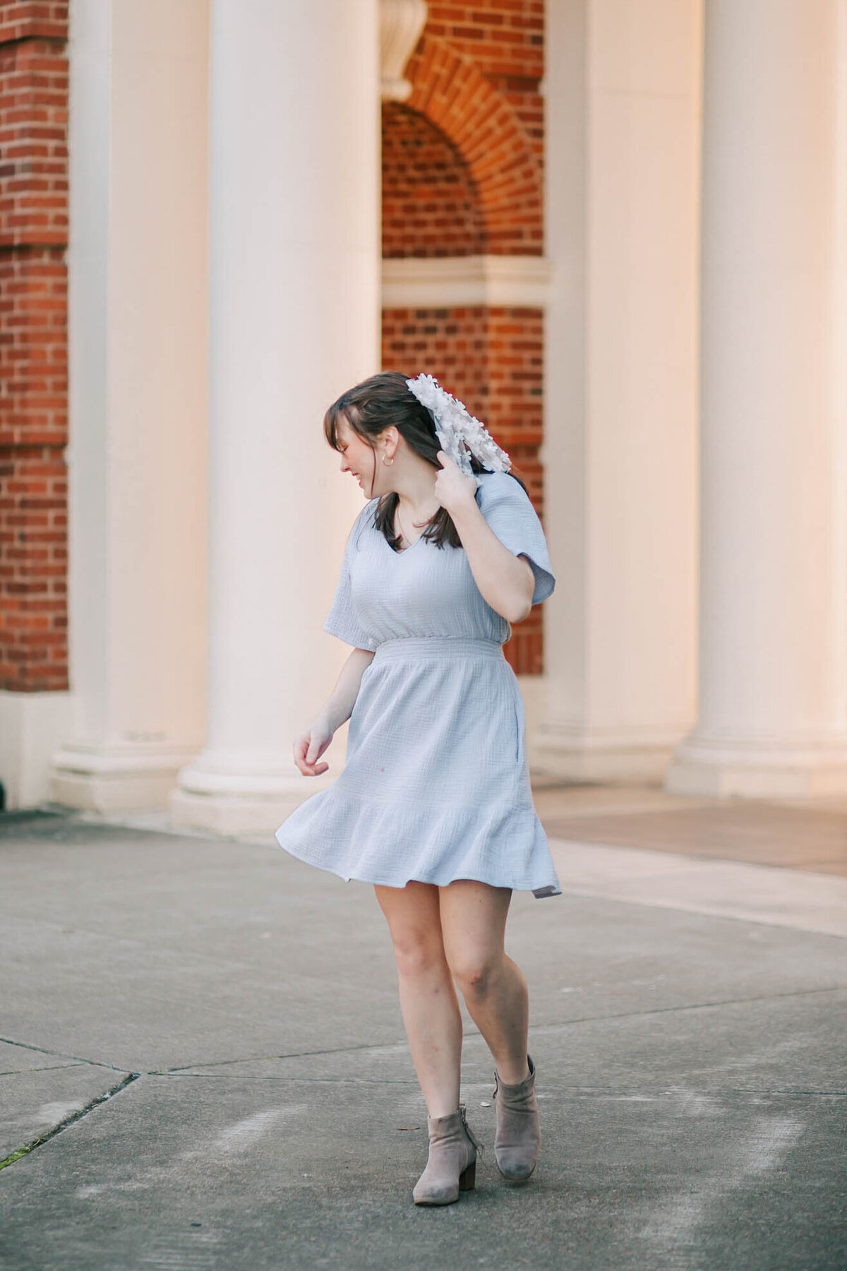 A girl in a blue dress looks down at the ground smiling