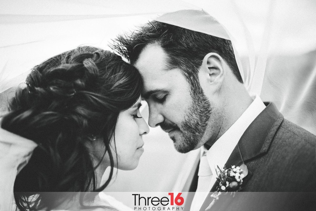 Tender moment between Bride and Groom with their eyes closed and foreheads touching under her veil