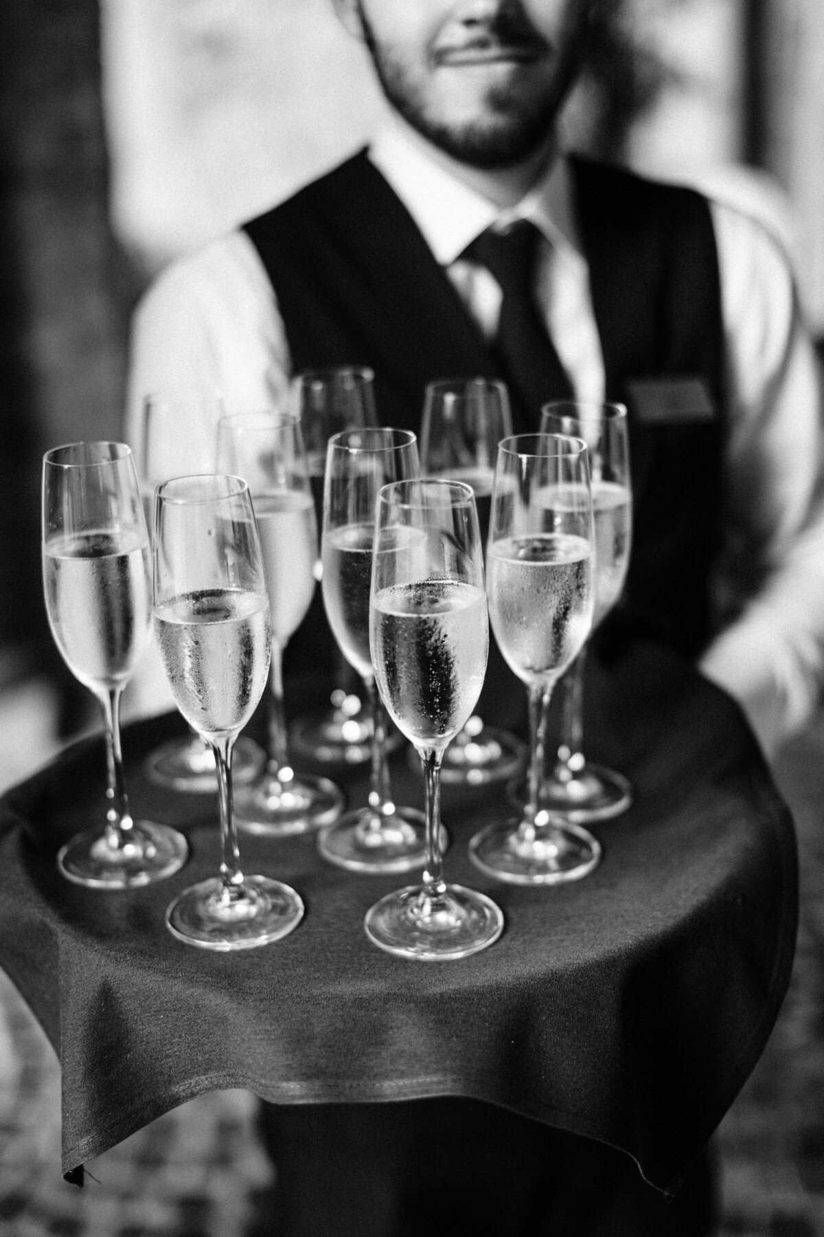 Black and white photo of a server holding champagne flutes at a Sarasota wedding.