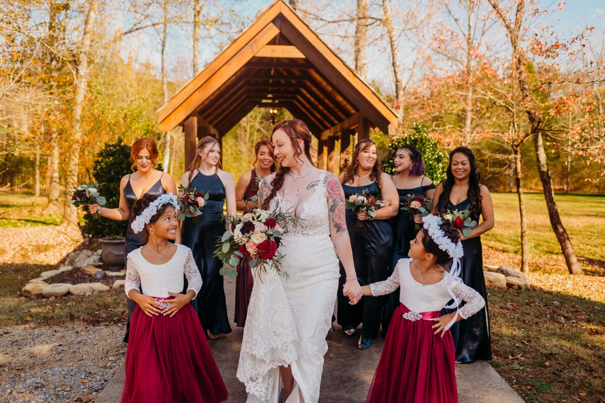 photo of a bride holding hands with the flower girls and walking while her bridesmaids walk behind her
