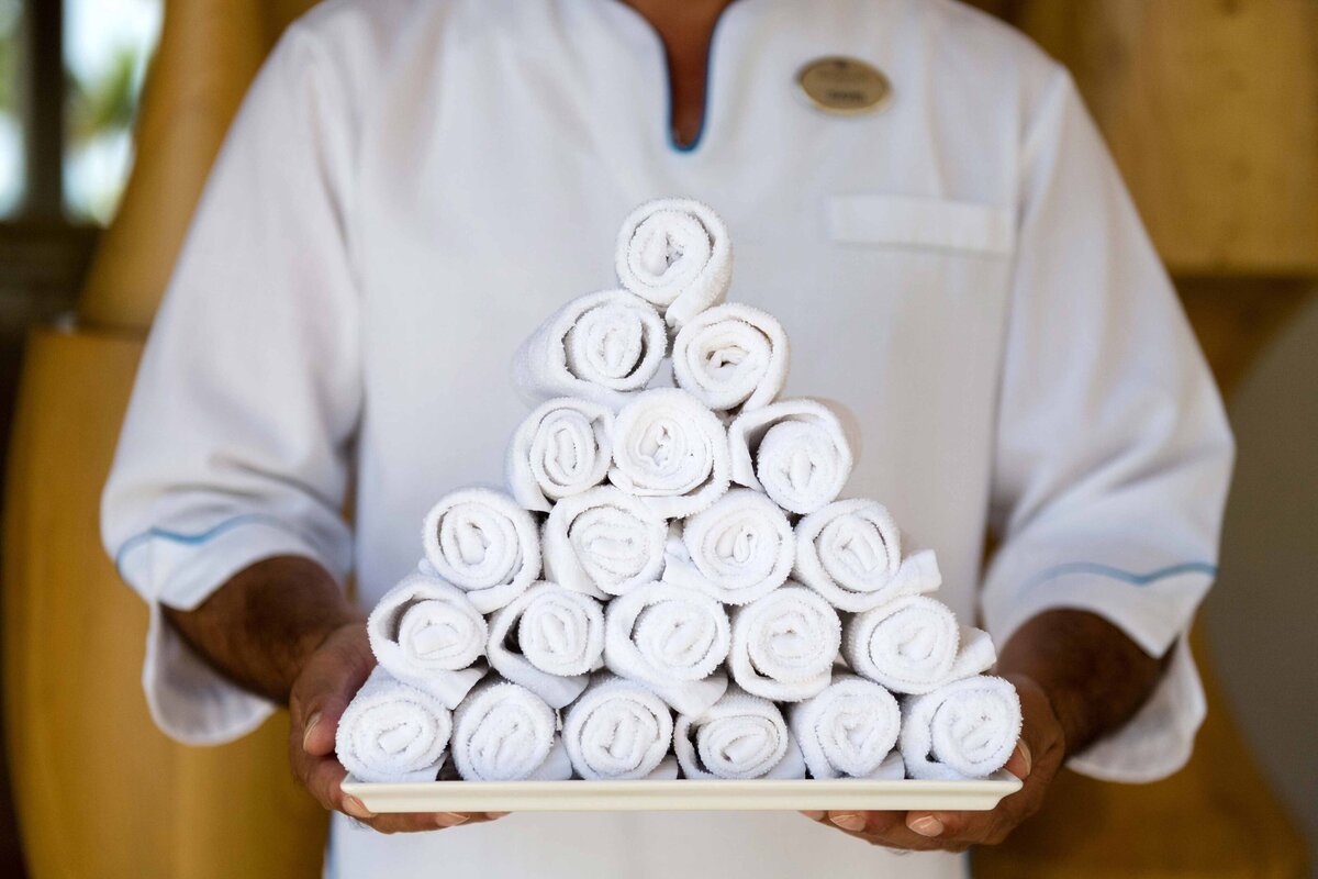 Rolls of hot towels are stack in a pyramid on a tray held by a resort staff member at the Paradisus. Warm towels are given upon arrival. Towels symbolize the caliber of the resort amenities