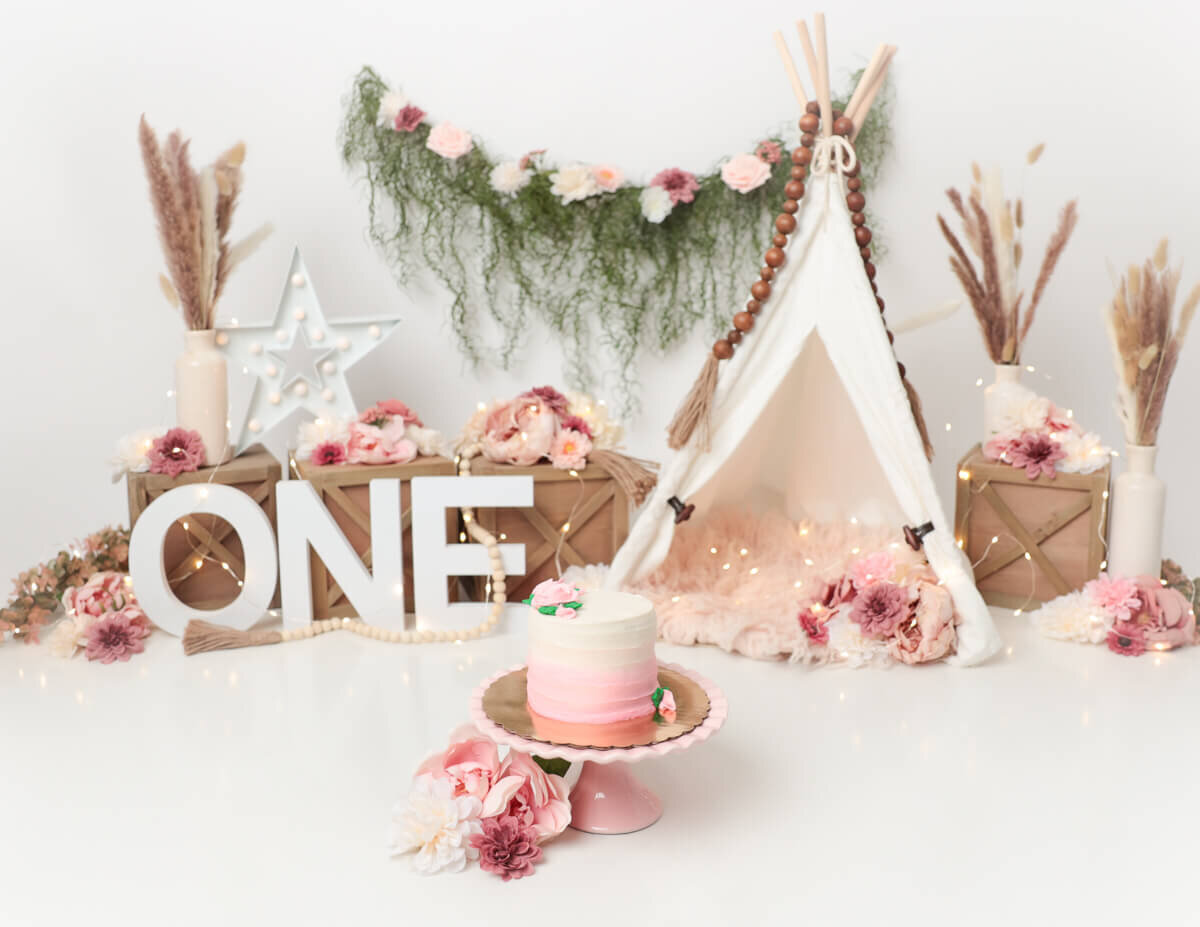 Creative boho-themed props, including cloth backdrops and floral arrangements, used in cake smash photography sessions in Rochester, NY.