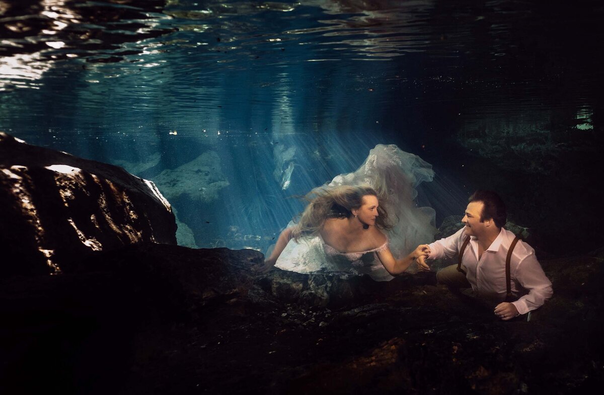Bride and groom swimming towards the camera  in underwater Trash the dress in riviera Maya