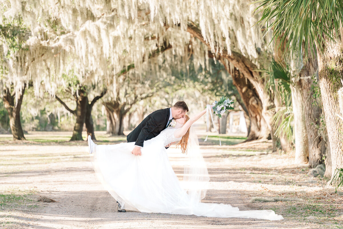 A groom dipping his wife in a kiss in St. Helena Island by JoLynn Photography, a North Carolina wedding photographer