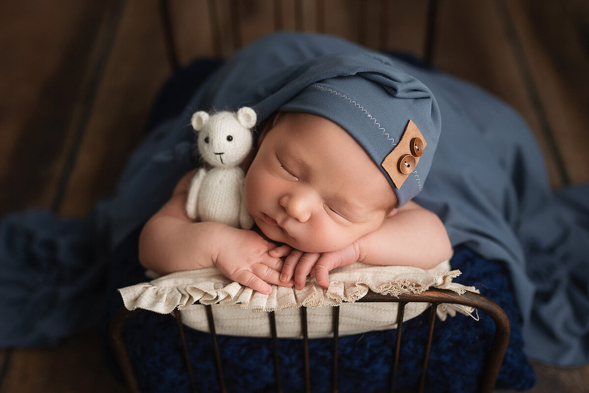 Baby boy sleeping with a white stuffed bear.