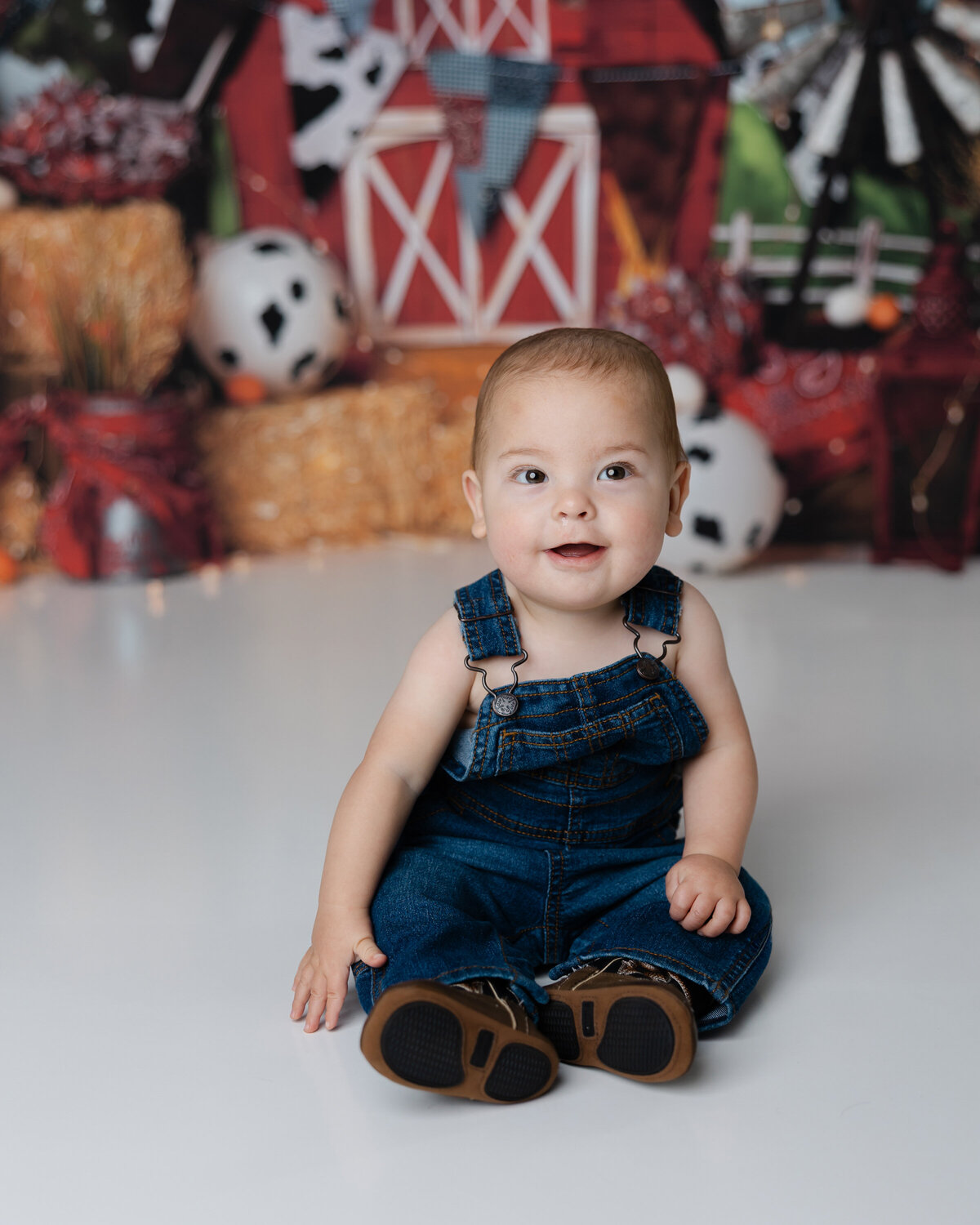Denim overalls, the sweetest grin, and a farm setup full of charm. Captured by Yucaipa cake smash photographer Kaitlyn Dawn Photography.