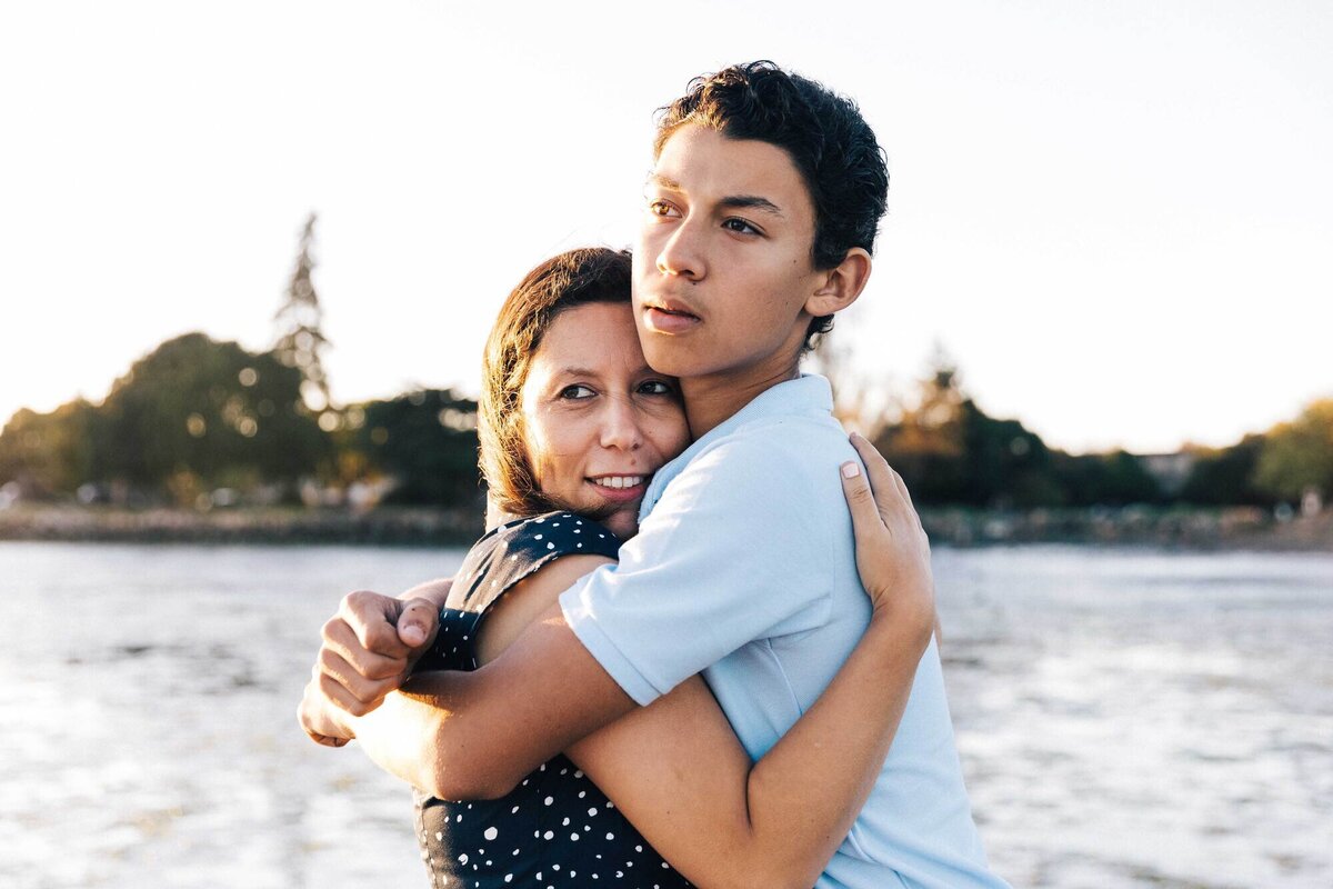 mother holding teenage son at crown memorial beach in alameda.