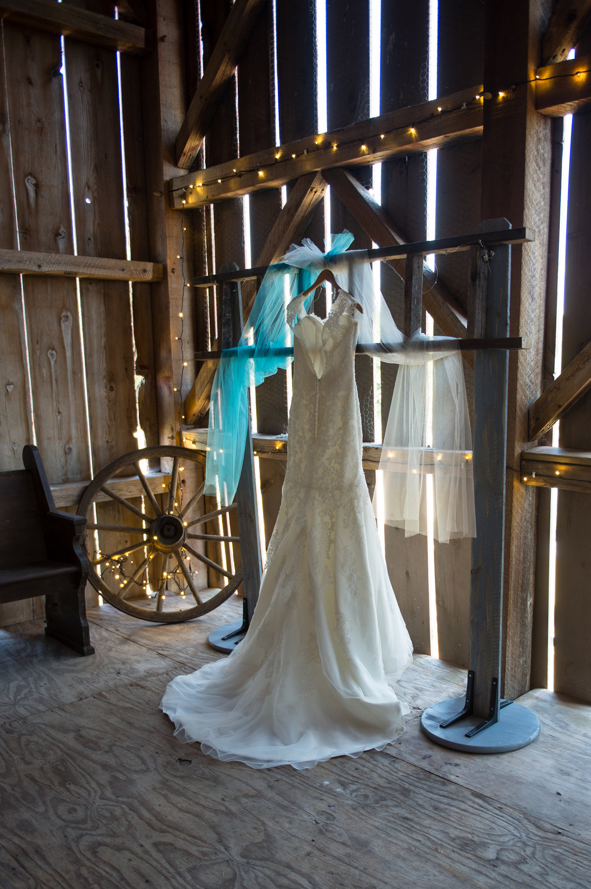 dress hanging in barn with wagon wheel