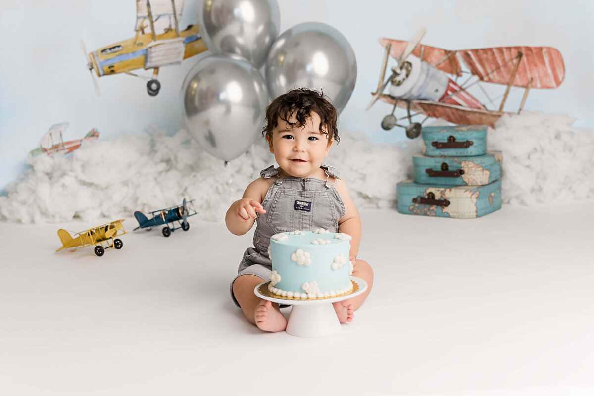 Portland Milestone Photographer image of adorable baby boy with airplane cake in first birthday studio session