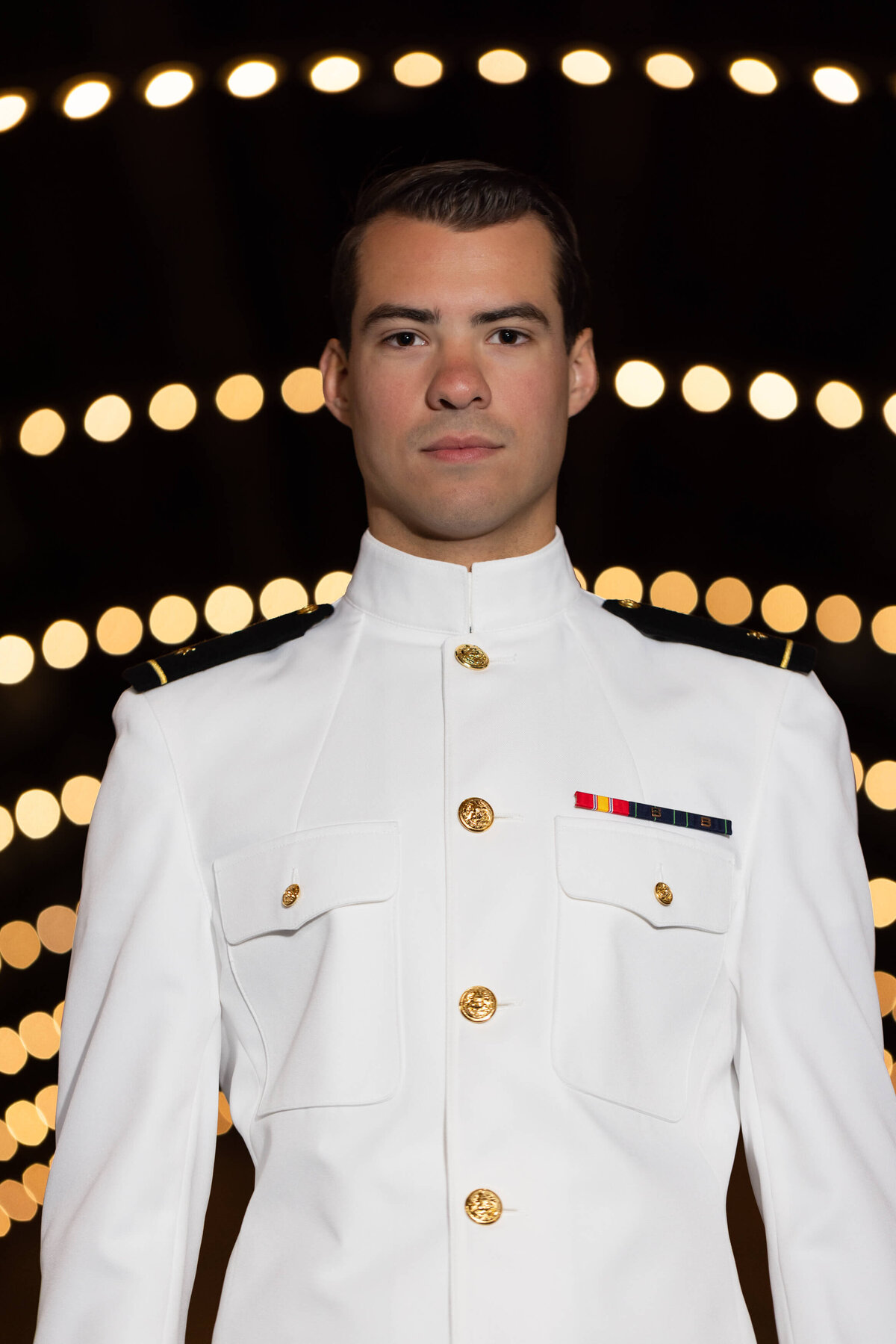 US Navy Officer in Dhalgren Hall lights in white uniform for senior photography in Annapolis, Maryland.