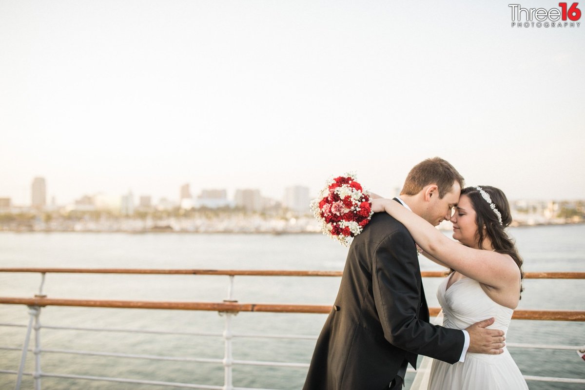 Bride and Groom embrace each other with foreheads touching in a tender moment with the ocean in the background