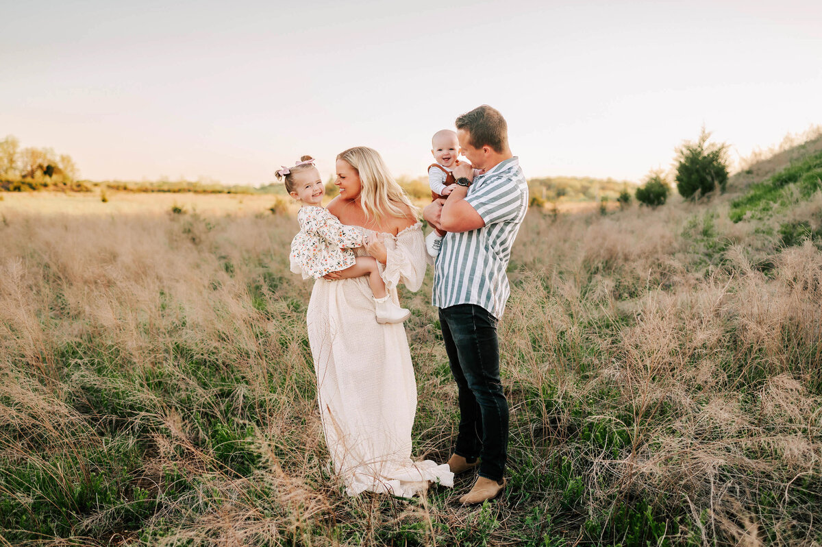 family laughing on hillside at sunset during Springfield MO family photography session