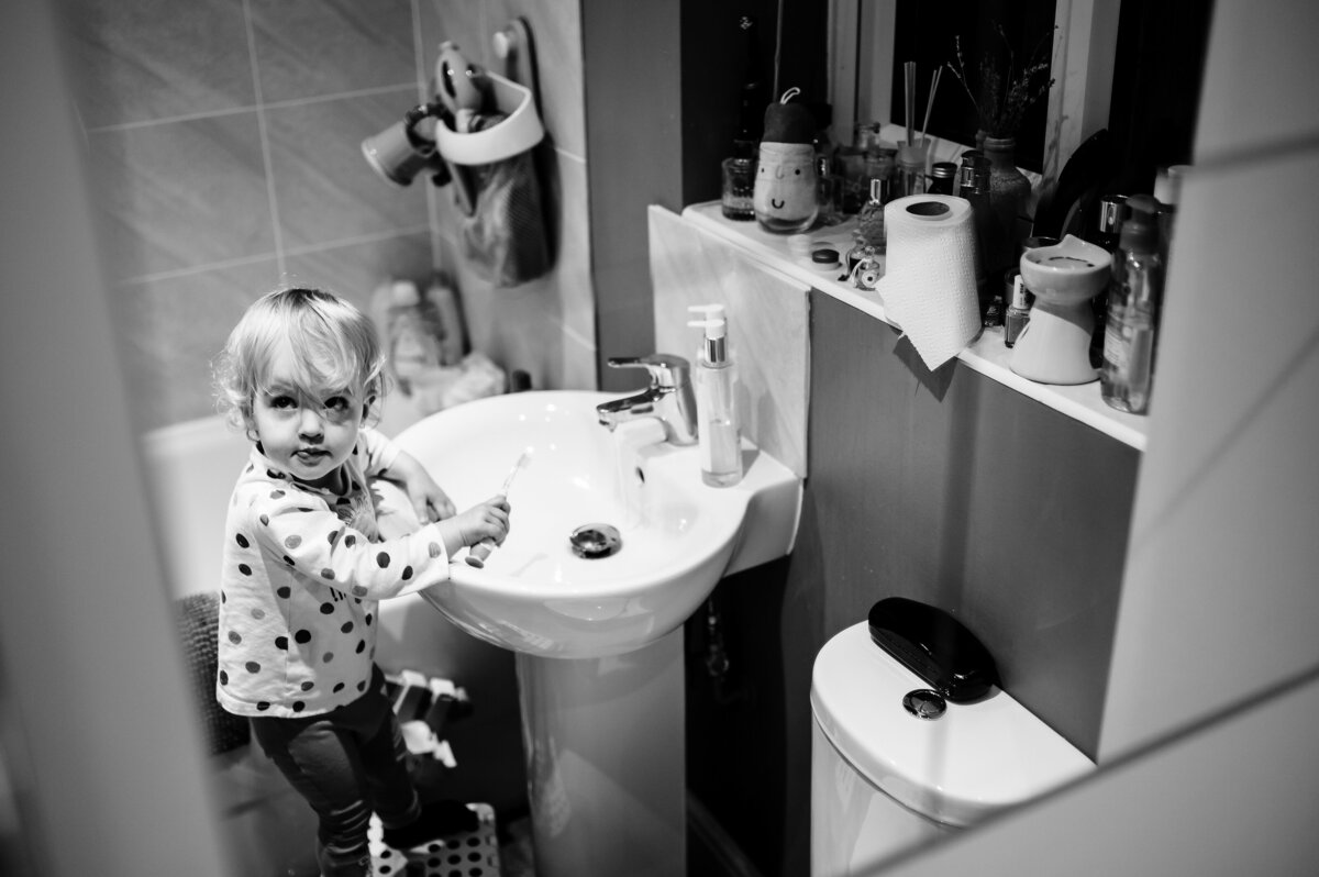 Little girl on step brushing her teeth during family photoshoot with amanda forman photography