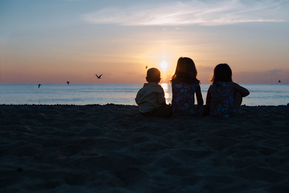 three young kids in silhouette watching the sunset