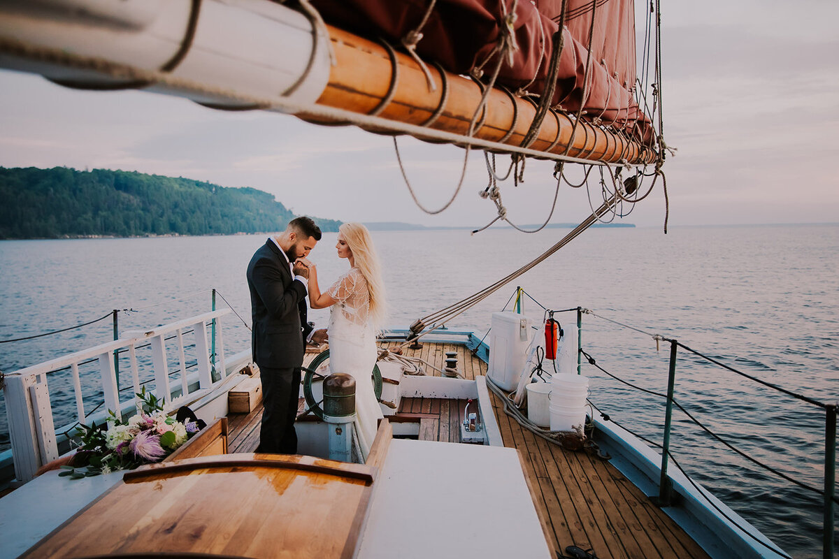 A man kisses a woman's hand on a sailboat in Door County WI