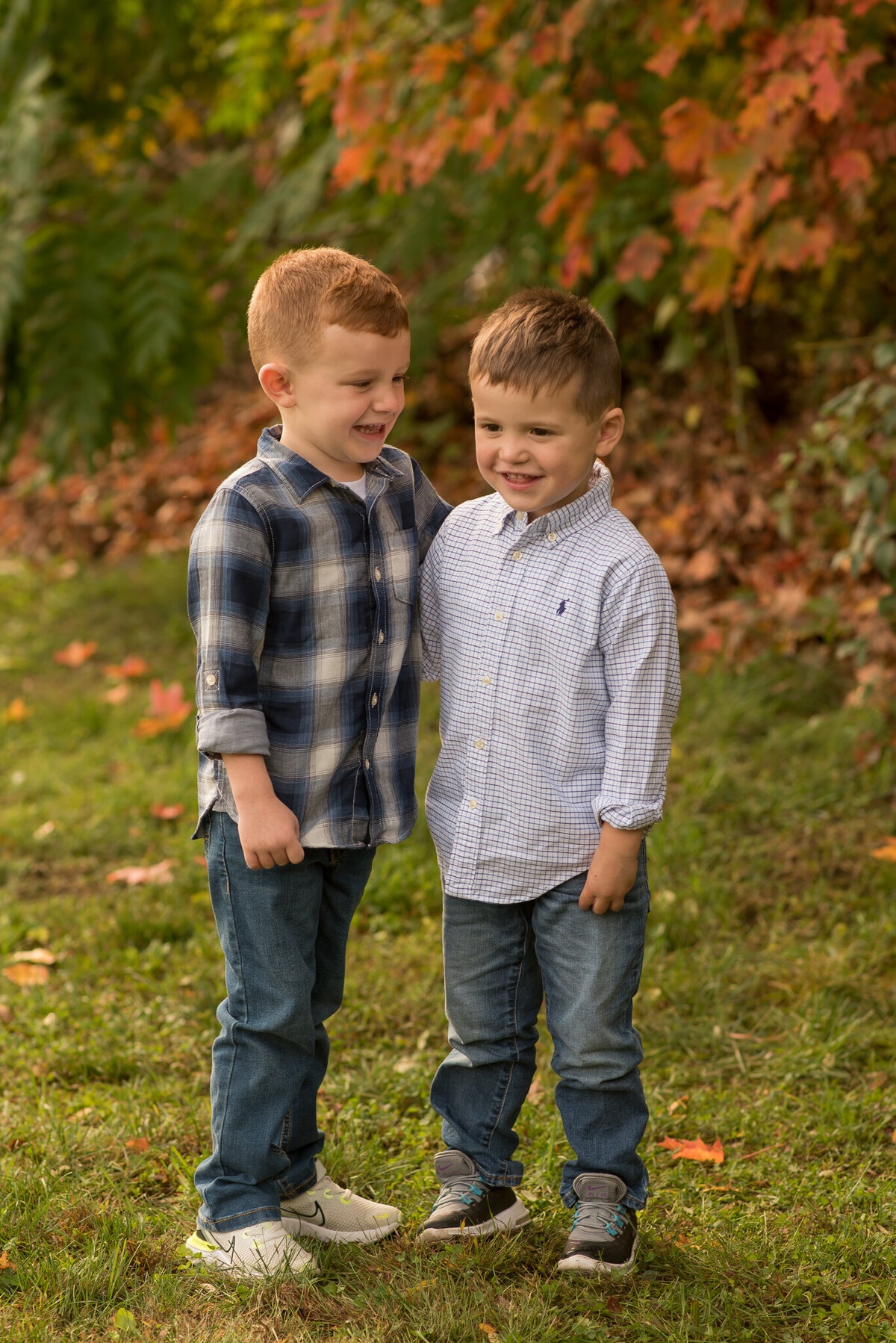 Two brothers laughing with fall leaves in the trees
