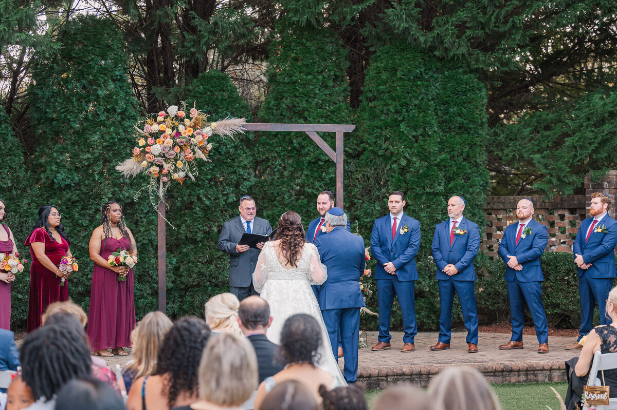 A bride being walked down the aisle by her father with the groom at the altar waiting  for her by JoLynn Photography, a Raleigh wedding photographer