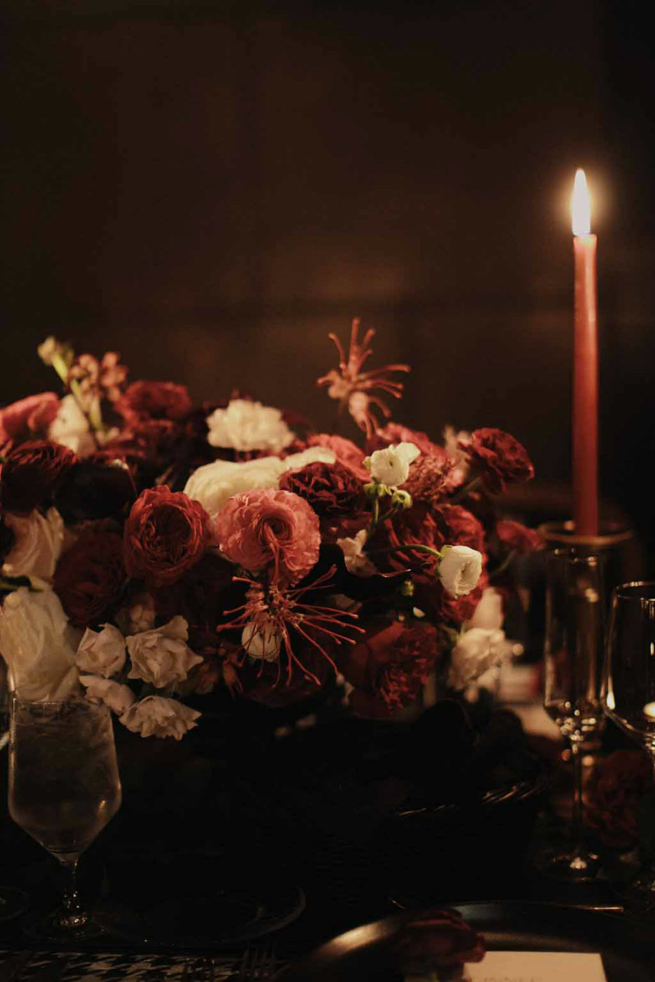 Burgundy ranunculus and cream spray roses with touches of red grevillea make up these centerpieces.