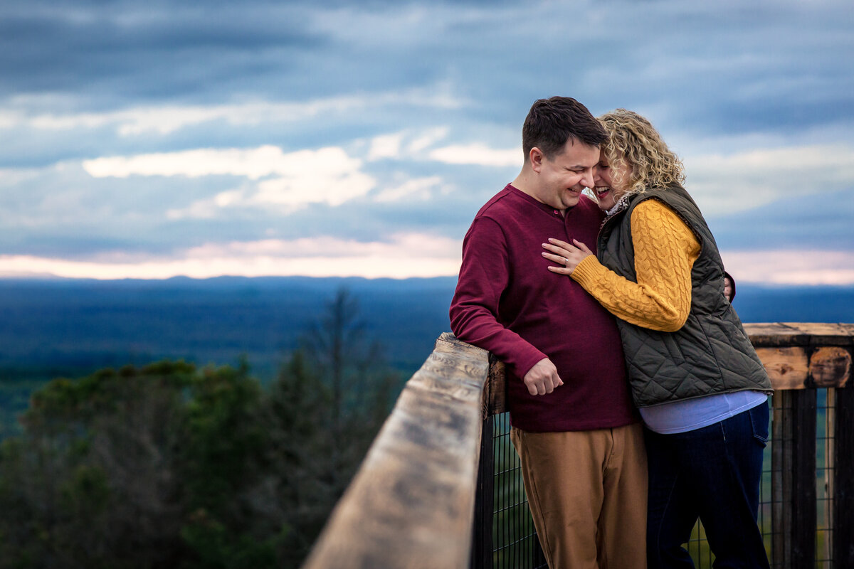 Couple gets close and laughs for their engagement session at Mount Agamenticus in Maine