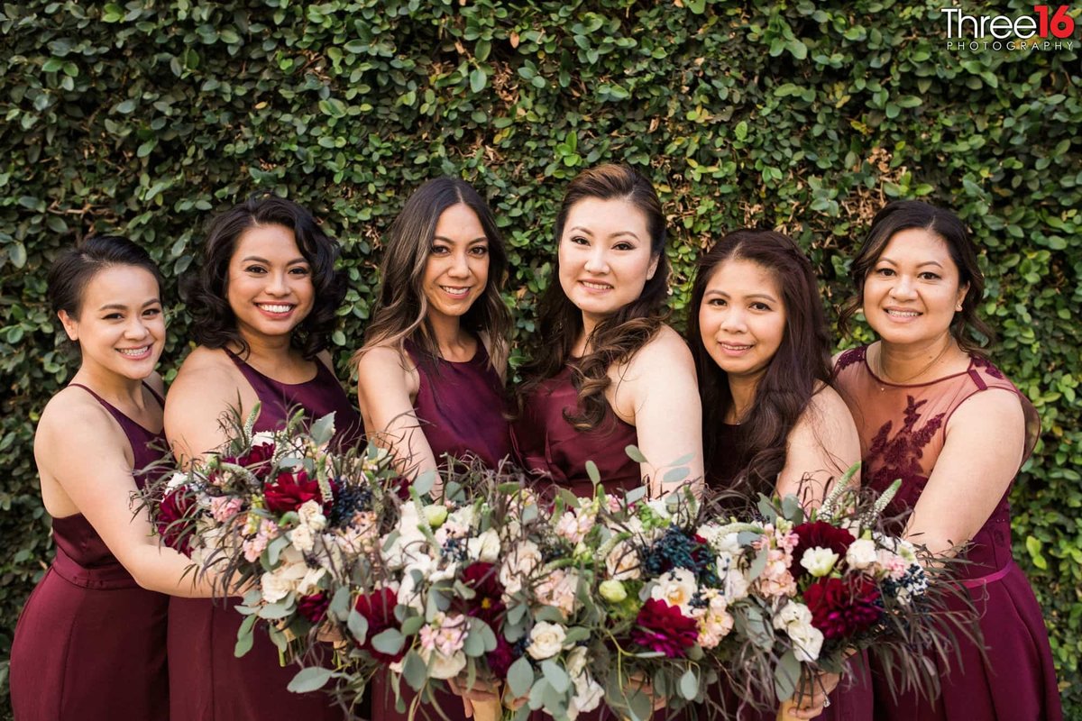 Bridesmaids pose together combining their bouquets
