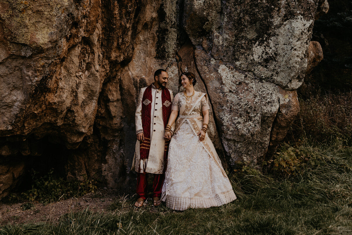bride and groom leaning against a massive rock in New Mexico