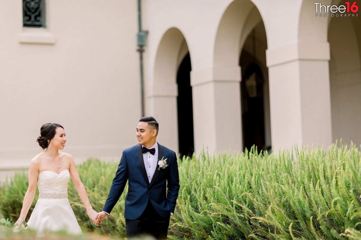 Bride and Groom walk hand in hand around the outside of the NOOR wedding venue in Pasadena