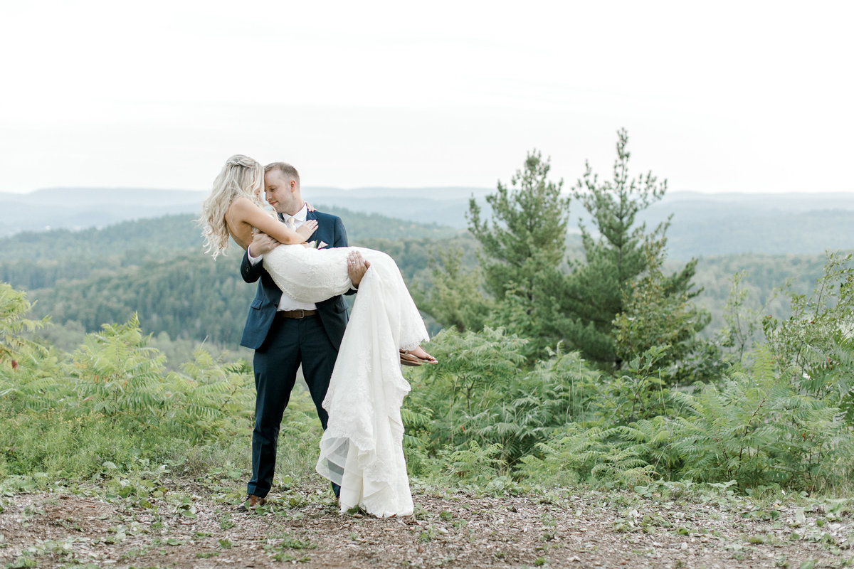 groom carrying bride on mountain top
