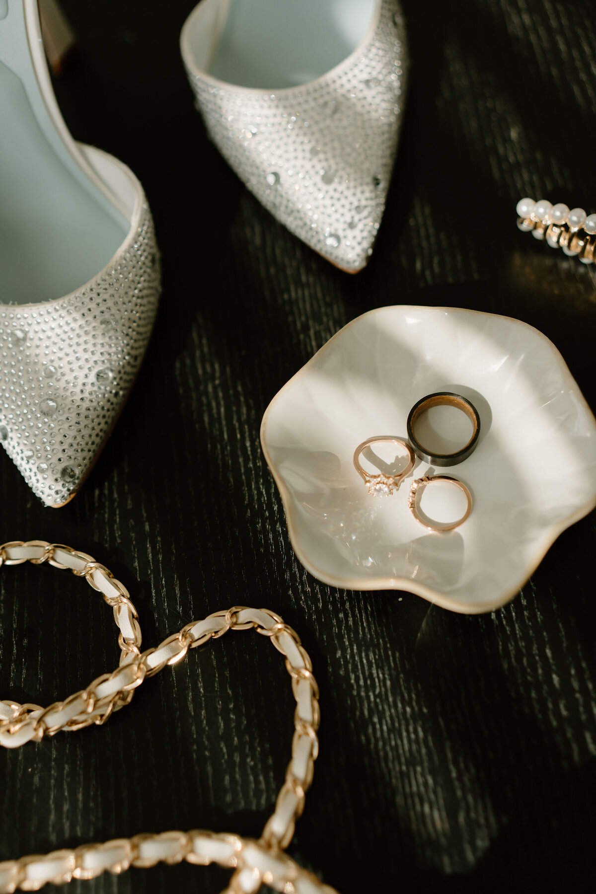 Details of wedding rings, bride's heels, and her purse